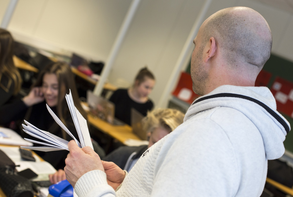 Lærer i klasserommet med papirbunke