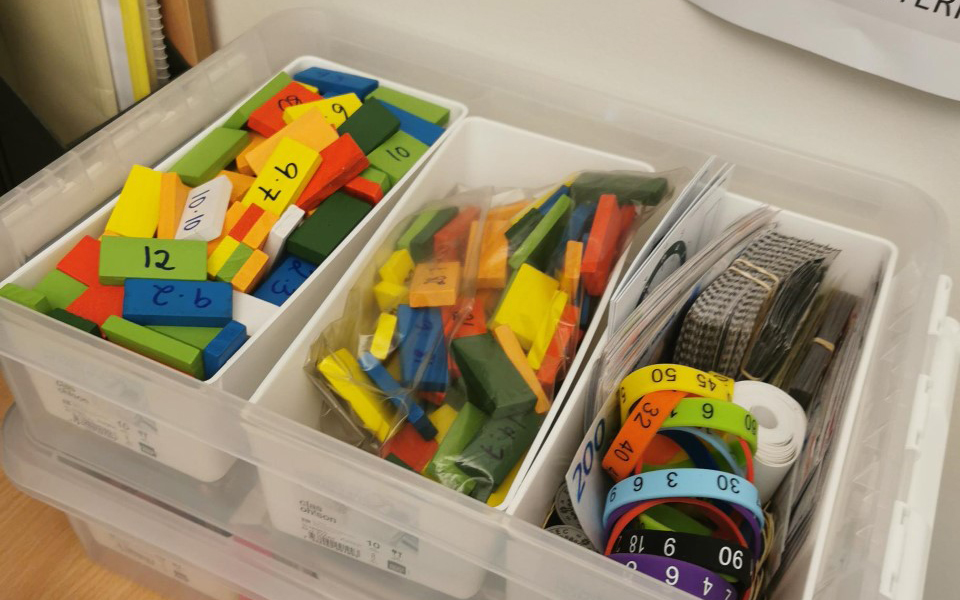 Tre plastbokser som inneholder ulike hjelpemidler til matematikkundervisning. Fotografi.