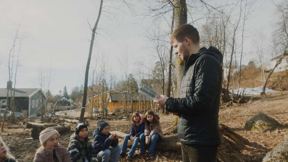 Marius snakker til en gruppe barn ute i naturen